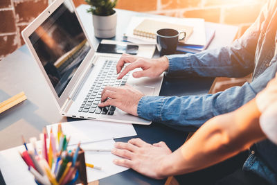 Midsection of man using laptop on table