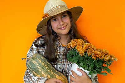 Portrait of young woman wearing hat against yellow background