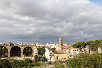 Buildings in city against cloudy sky