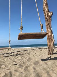 Low angle view of swing on beach against clear sky