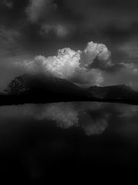 Scenic view of lake and mountains against storm clouds