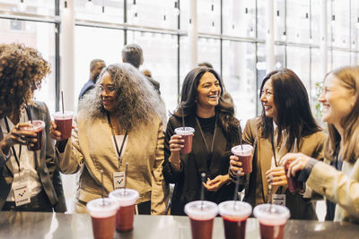 Happy female delegates having smoothies during break time at convention center