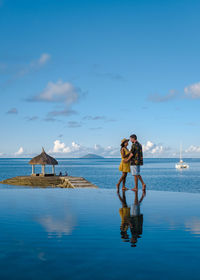 Happy couple standing against sea