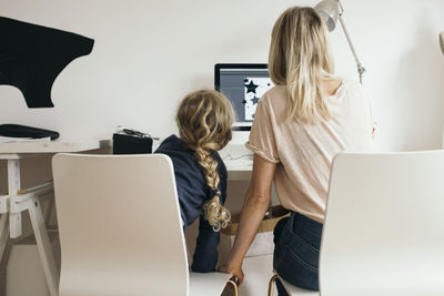 Rear view of girl with mother using laptop at home