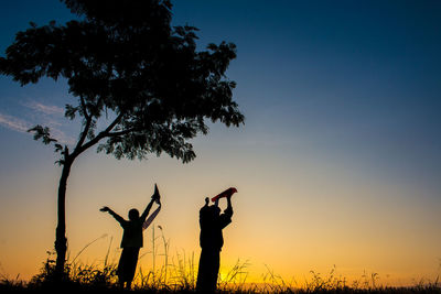 Silhouette children and tree against sky during sunset