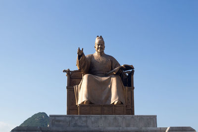 Low angle view of statue against clear blue sky