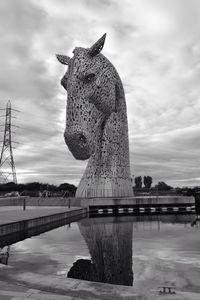 Statue in city against cloudy sky