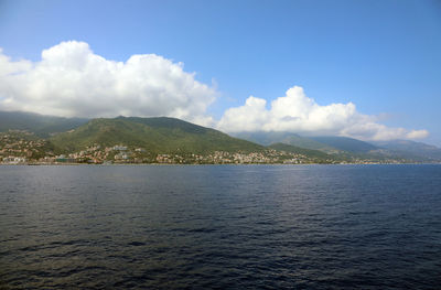 Scenic view of sea by mountain against sky