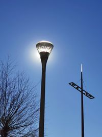 Low angle view of illuminated street light against blue sky