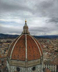 View of church in city against cloudy sky