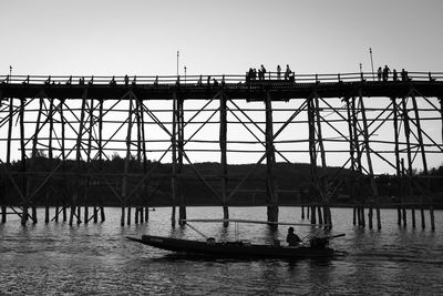 Silhouette people on bridge over river against clear sky