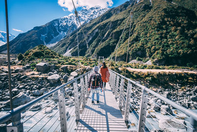 Rear view of woman and man walking on footbridge