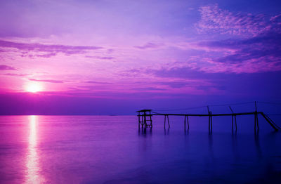 Silhouette pier over sea against sky during sunset