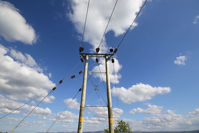 Low angle view of electricity pylon against blue sky