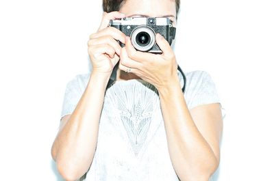 Portrait of man photographing against white background