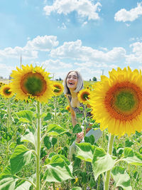 Portrait of smiling woman standing amidst sunflower field