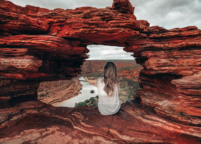 Rear view of woman sitting on rock formation