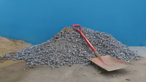 Metallic structure on sand at beach against blue sky