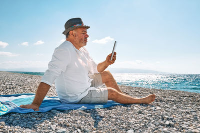 Side view of woman sitting on beach against clear sky