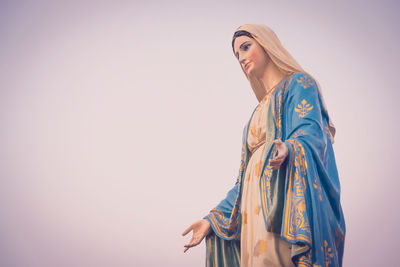 Low angle view of woman looking away against sky