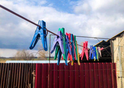 Clothespins on clothesline against sky