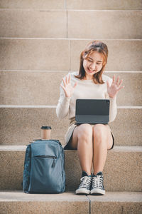 Young woman using digital tablet sitting on steps outdoors