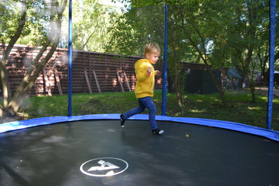 A boy on a trampoline in the garden.