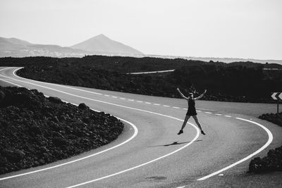 Front view of woman jumping on road