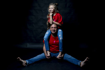 Portrait of a smiling girl sitting against black background