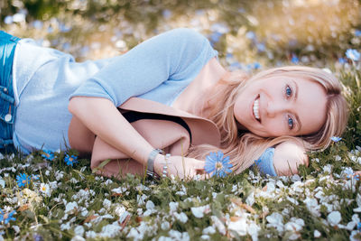 Portrait of young woman lying on field