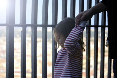 Midsection of mother holding daughter hand by fence