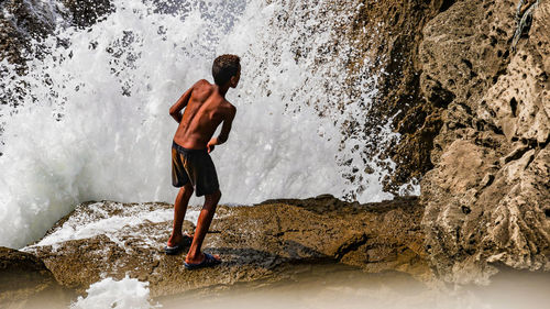 Full length of shirtless man standing on rock