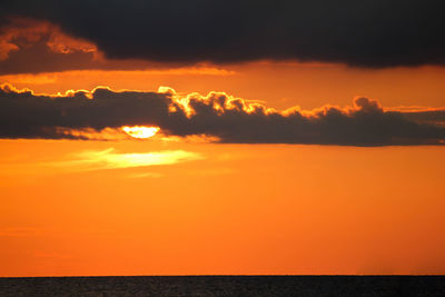 Scenic view of sea against dramatic sky during sunset