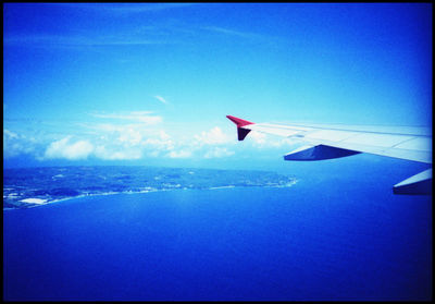 Close-up of airplane flying over sea against blue sky