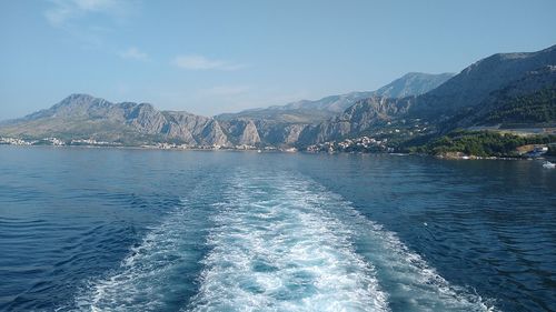 Scenic view of sea by mountains against sky