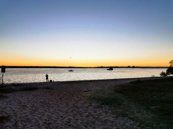 Scenic view of beach against clear sky during sunset