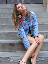 Full length of young woman sitting on staircase