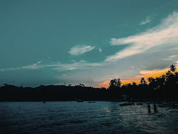 Silhouette trees by sea against sky during sunset