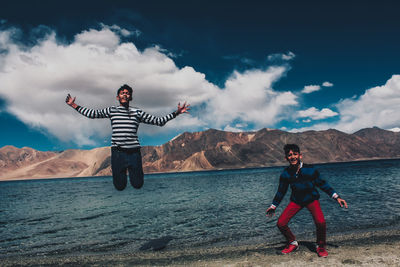 Full length of men with arms raised against sky