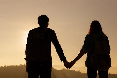 Silhouette couple standing against sky during sunset