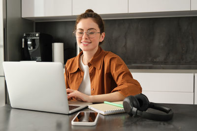 Portrait of young woman using laptop at office