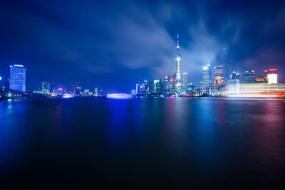 Illuminated city by buildings against sky at night