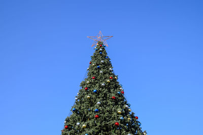 Low angle view of christmas tree against clear blue sky