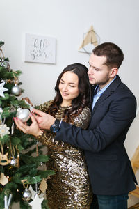 A man and a woman in love are preparing together and celebrating new year and christmas at home