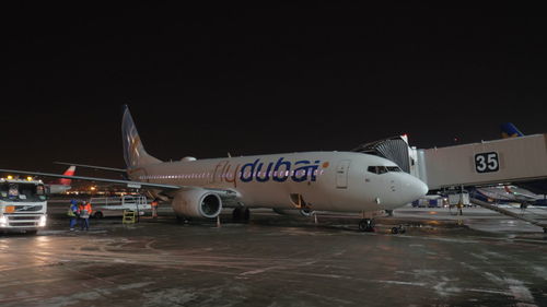 Airplane on airport runway against sky at night