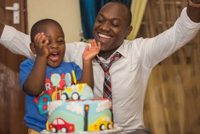 Cheerful father and son with birthday cake at home