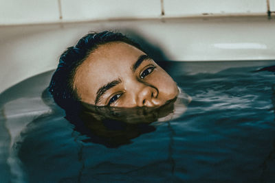 Close-up portrait of young woman in bathtub