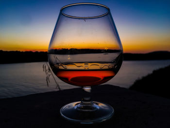 Close-up of beer in glass against sky during sunset