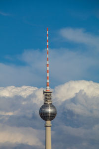 Low angle view of communications tower against cloudy sky