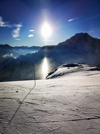 Scenic view of snow covered mountains against bright sun
